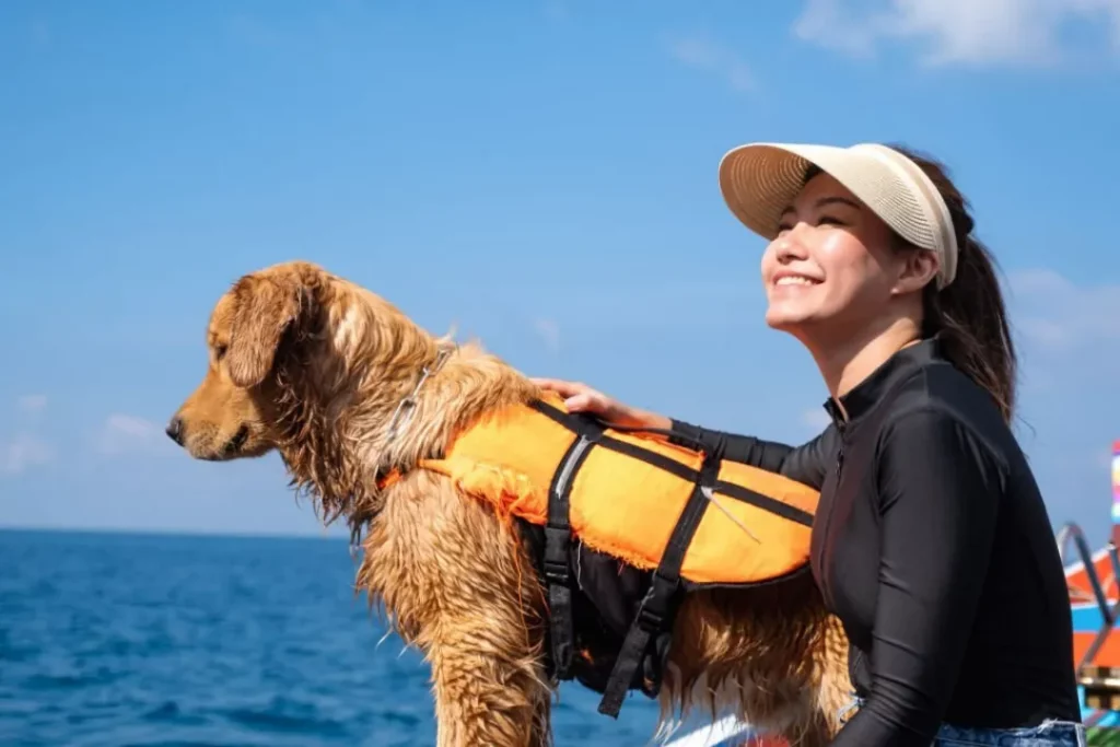 a beautiful young asian woman and a golden retriever dog with life jacket